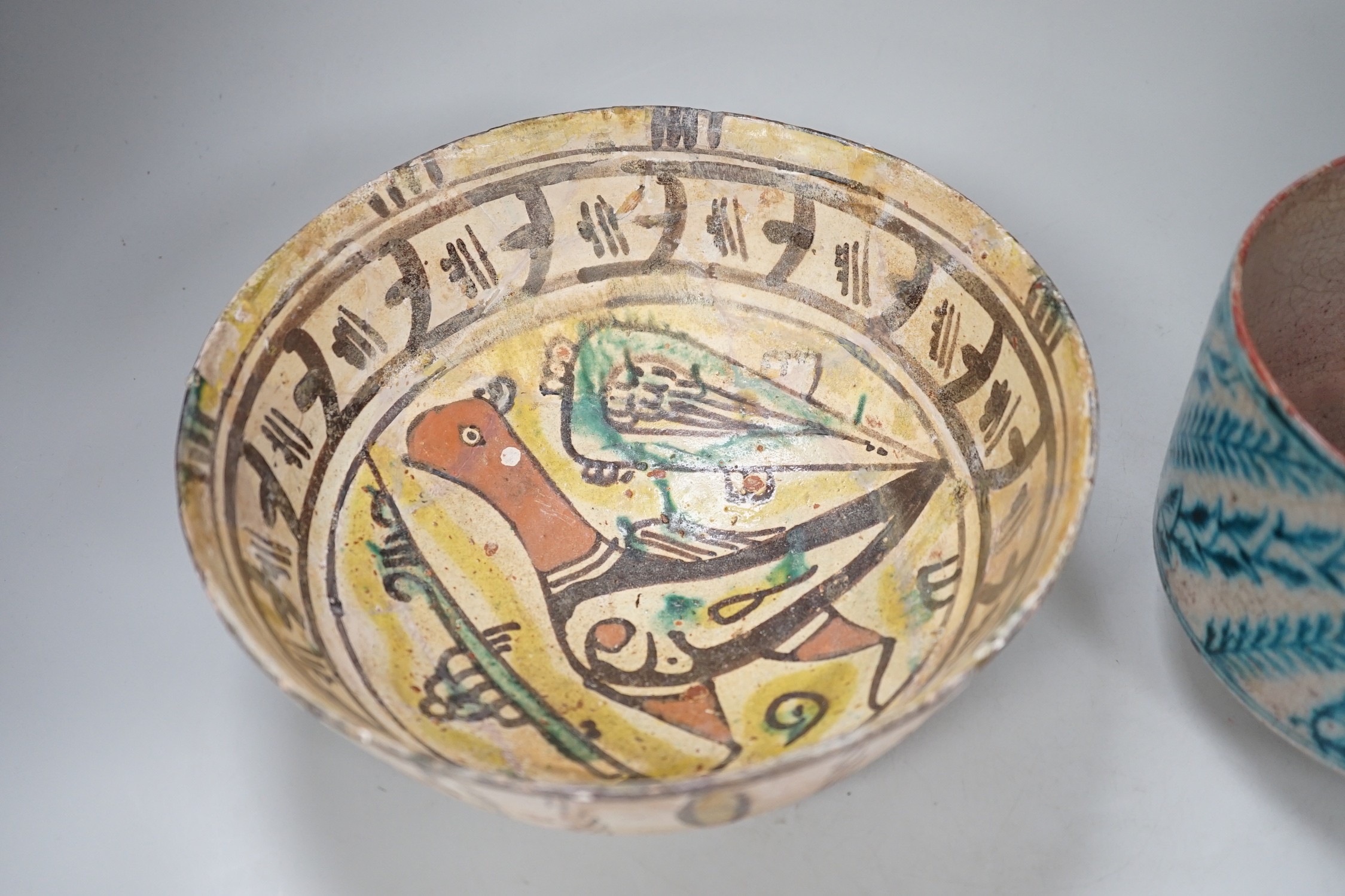 An Islamic Persian bowl with turquoise blue leaf design, 15cm diameter, together with a section of an Islamic tile, and another Islamic bowl, possibly Kashan. Tallest 11cm